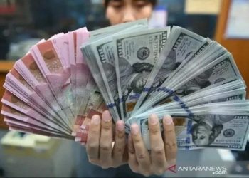 Ilustrasi: Teller menunjukkan lembaran rupiah dan dolar AS (ANTARA FOTO)