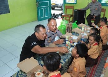 Anggota Polres Blitar Kota bercengkrama dengan anak-anak SD saat uji coba program makan bergizi gratis, Jumat (6/12/2024).