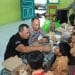 Anggota Polres Blitar Kota bercengkrama dengan anak-anak SD saat uji coba program makan bergizi gratis, Jumat (6/12/2024).